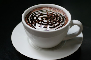 Fototapeta premium Hot cappuccino white coffee cup with latte art on black table background in cafe. Food and drink concept.