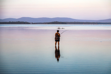 Woman fishing in lake with reflection in water