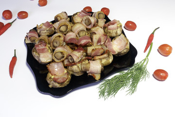 Mushrooms stuffed with bacon and cheese, on a black dish, ready to eat, isolated on white background.