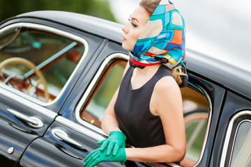 Beautiful young woman in vintage dress with retro auto