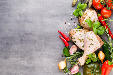 Spicy chicken legs, fresh vegetables on a gray background.Top view.
