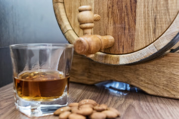 A small wooden oak barrel for home production and a stack of whiskey aged in it