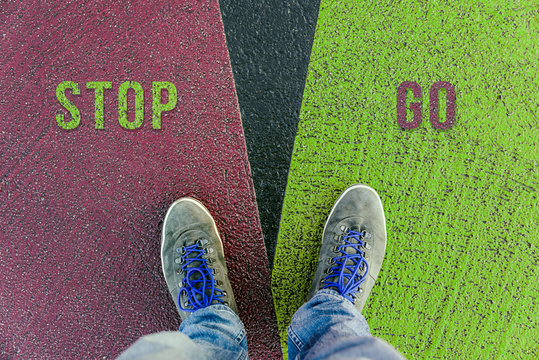 Concept of facing a crucial decision about stop and go shown by shoes on different colored pathways
