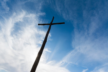 Wooden christian cross under a cloudy sky.