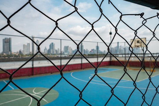 basketball court behind fence with city skyline background