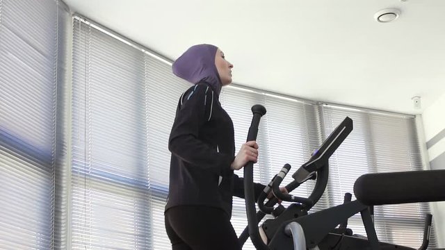 portrait muslim sportswoman woman in hijab on step exerciser in gym
