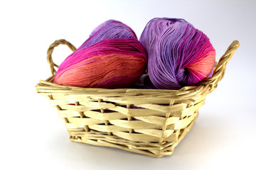 Clusters of sectional yarn for needlework in a wicker basket on a white background close-up