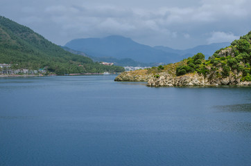 Summer view panorama before storm beach sea water palm rest calm sunny weather high mountains background of yachts and ships exotic green nature vocation Aegean sea Turkey