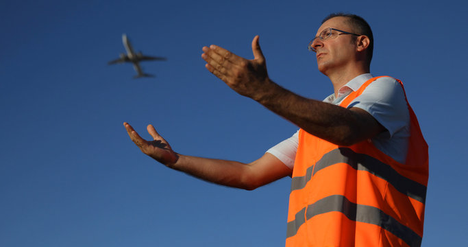 Ground Crew Worker Man Standing and Marshalling Directing an Aircraft on Arrival Show Position in Airport Area