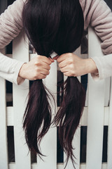 Girl holds her hair over the fence