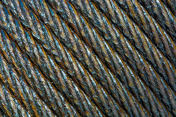 The steel rope is packed in rows. It is covered with a translucent grease of brown color. The photo looks like a background