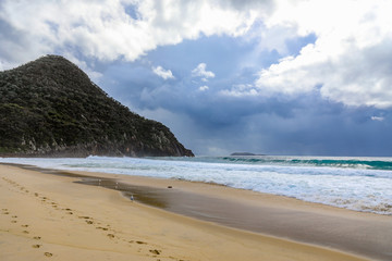 Footprints on sandy beach against mountain and ocean