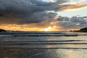 Sunrise shining through stormy sky over beach