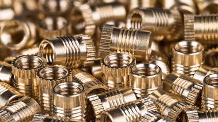 Bronze threaded inserts as background. Close-up of decorative pile from golden metal parts. Idea of...
