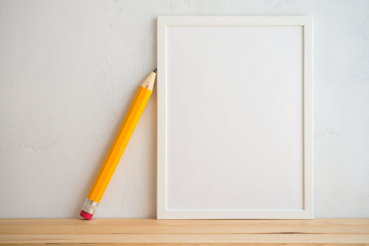 Photo frame and pencil on white wall background, creative ideas back to school concept