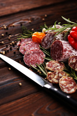thinly sliced salami on a wooden texture on the background.