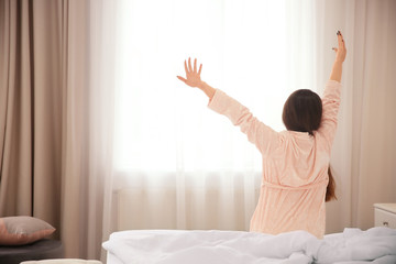 Young woman stretching on bed in hotel room