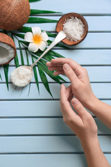 Fototapeta na wymiar Young woman applying coconut oil on wooden background, closeup