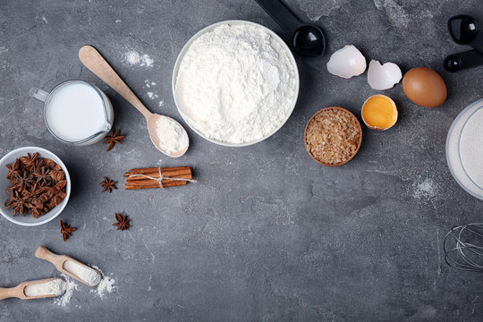 Flat lay composition with flour, eggs and jug of milk on grey background