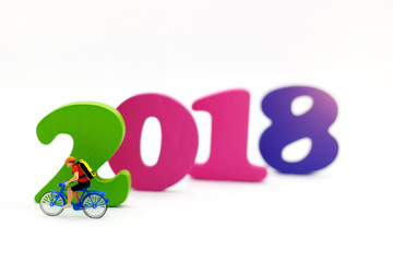 Miniature people: Traveler riding bicycle  with number 2018. Travel and Sport concept.