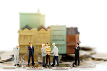 Miniature people: Business team  meeting with coins stack and homes. Business planning and...