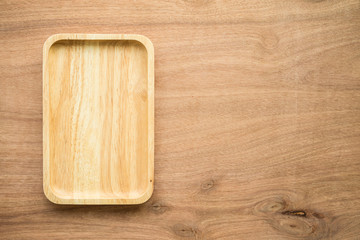 Top view of unused brand new brown handmade wooden dish plate on wooden table background