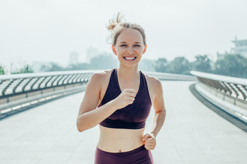 Closeup portrait of smiling young attractive woman wearing sportswear, training and jogging on...