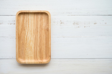 Top view of unused brand new brown handmade wooden dish plate on white wooden table background
