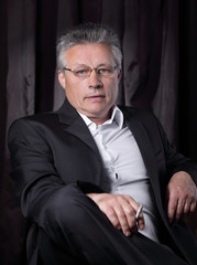 Fototapeta premium senior businessman with a cigarette,sitting in a chair