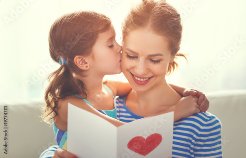 Happy mother's day! Child daughter congratulates moms and gives her a postcard