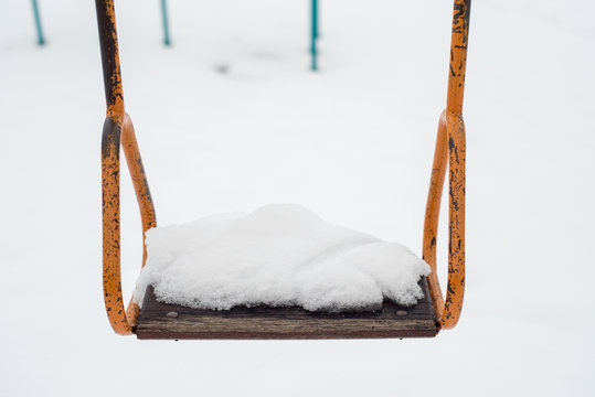 Empty swing in winter time with snow 