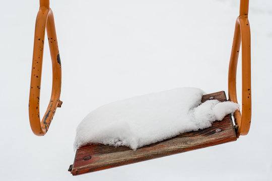 Empty swing in winter time with snow 