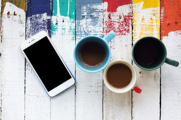 close up of smartphone and cups of coffee background