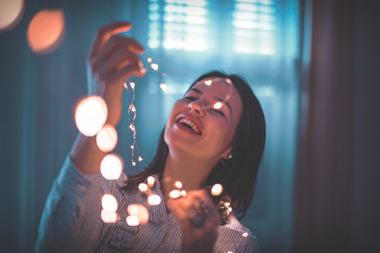 Young Woman Decorating Home With LED Fairy Lights