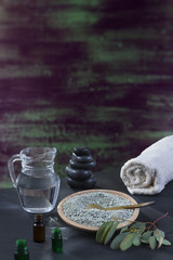 Beaty and Spa concept: glass mortar with eucaliptus leaf, essential oin, white towel cupp of clay on brushstrokes with thick paint in shades of green, blue, purple wooden texture