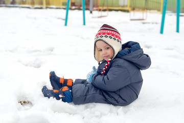 Fototapeta na wymiar Little boy sitting in snow and playing