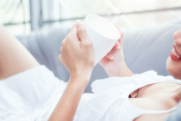 Obraz na płótnie Canvas Beautiful girl on bed with white coffee mug in hand.