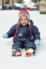 Fototapeta na wymiar Little boy sitting in snow and playing