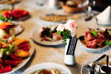 wedding table with delicious dishes and a small vase with roses