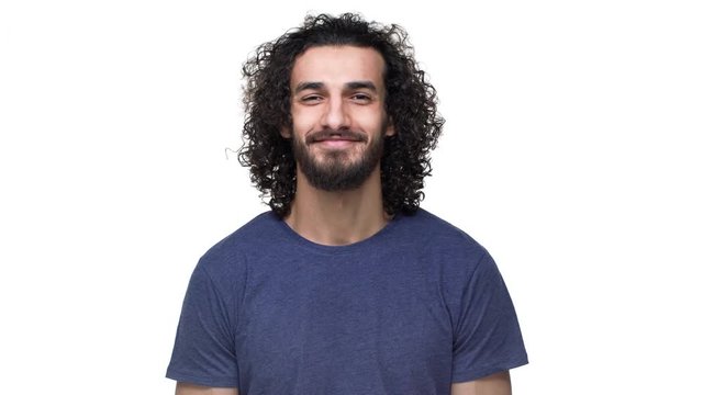 Closeup portrait of brazilian unshaved man in casual dark blue t-shirt expressing acceptance with smile, over white background. Concept of emotions