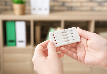 Woman holding test for HIV, Hepatitis B, C and Syphilis on blurred background