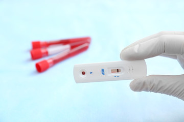 Obraz premium Doctor holding express test for HCV on blurred background