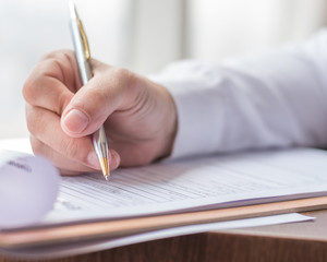 Applicant filling in company application form document applying for job, or registering claim for...