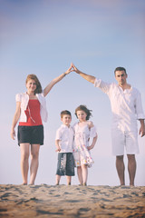 family on beach showing home sign