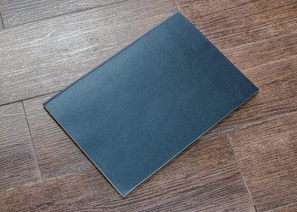 Black dark blank leather magazine cover book template on white grey wooden table background