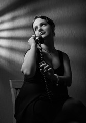 Dramatic portrait of a beautiful woman with old black phone .