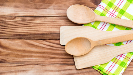 Wooden spoons and wooden spade with kitchen towel on the table. Top view. Copy space.