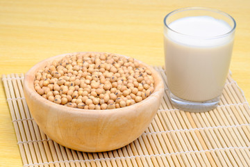 soy milk in glass and soy seeds in wooden bowl