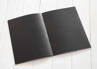 Blank A4 size black book template mock up with open double page placing on creamy white wood table