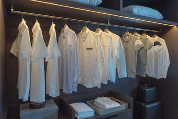 row of white shirts on rail in wooden closet